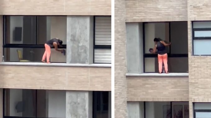 Mujer limpiando ventalanes en edificio de El Poblado